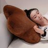 A person rests their head on a large, brown, star-shaped decorative throw pillow on a light-colored sofa.