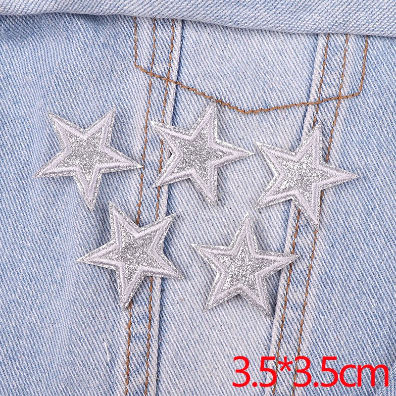 Five silver glitter star patches are embroidered onto a light blue denim fabric.