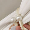 Close-up of cream colored pearl tiebacks used to secure a white curtain fabric.