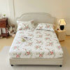 White floral printed cotton fitted sheet with matching pillow covers on a bed.