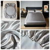 A set of satin bedding featuring a silver elastic band and luxurious draped fabric.