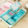 A light green travel organizer box filled with pink and blue mesh pouches for storing small items.