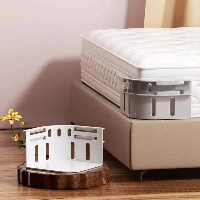 A set of white invisible bed sheet clips is displayed on a wooden surface next to a white mattress.
