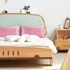 A light wood bed frame with pink and white pillows and a green headboard, featuring silky satin toddler pillowcases.