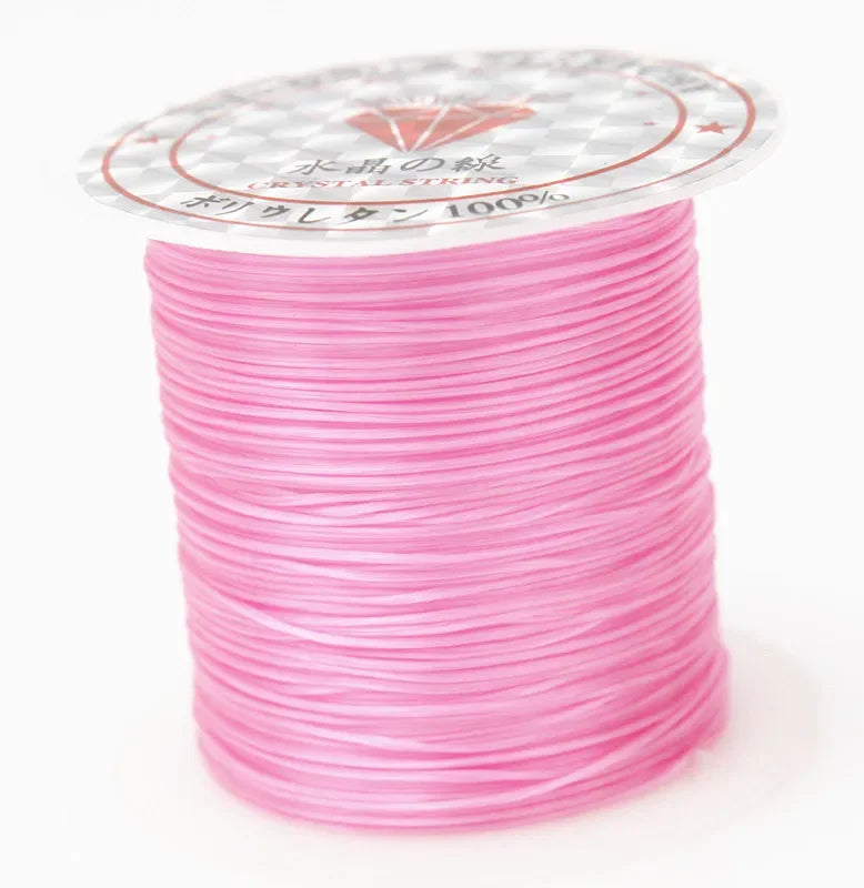 A spool of pink elastic beading cord with a label indicating polyester 100%
