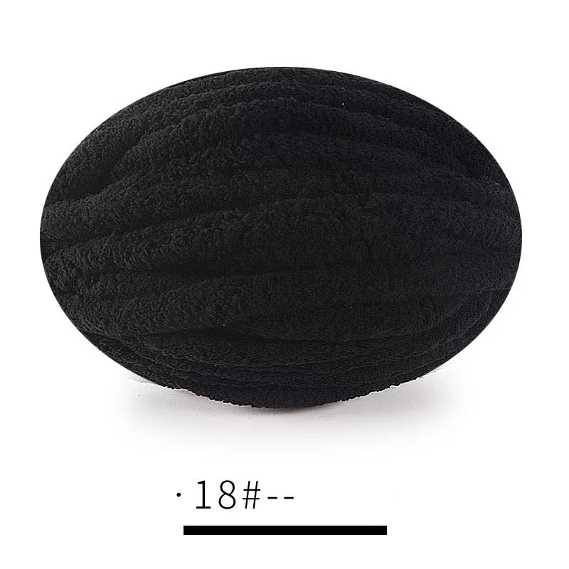 A ball of black extra thick hand-knitted yarn with a measurement scale below it.