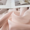 Soft blush pink reversible cooling quilt fabric draped in a flowing fold