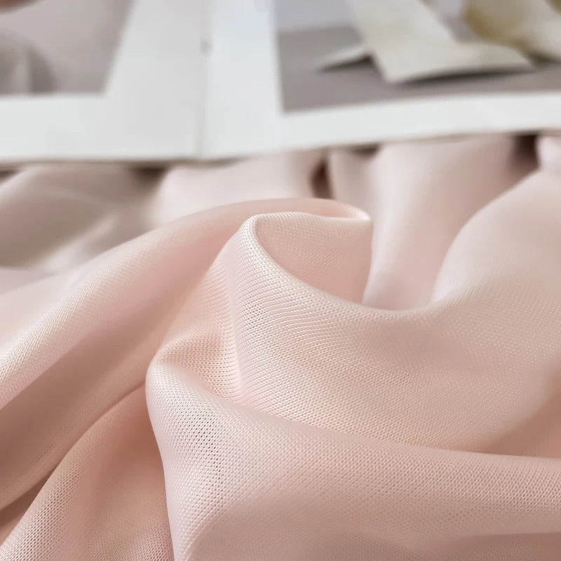 Soft blush pink reversible cooling quilt fabric draped in a flowing fold