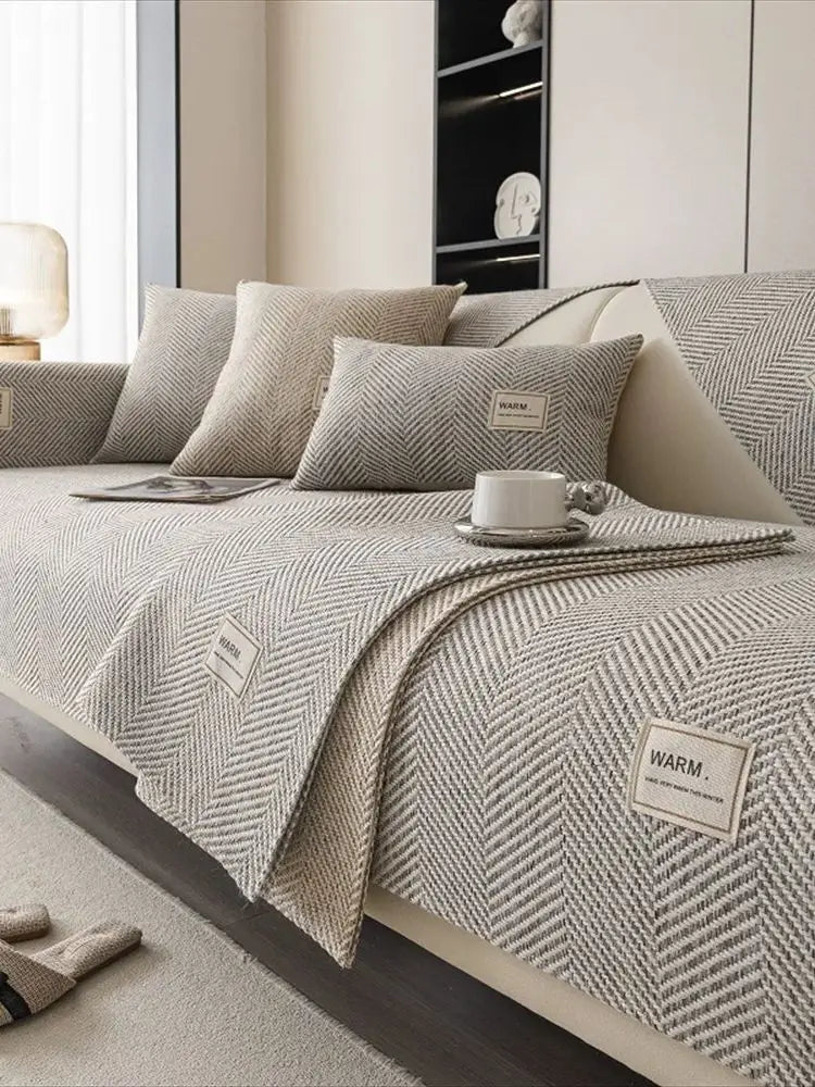 A close-up of a beige anti-slip sofa cover featuring a textured weave and decorative pillows on a light-colored sofa.