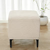 A beige geometric jacquard ottoman slipcover resting on a wooden floor.