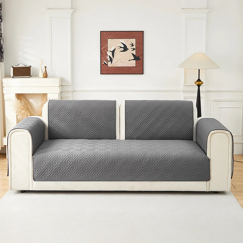 A modern gray geometric quilted sofa cushion cover on a white frame in a bright living room.
