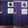 A close-up of a dark blue beaded string curtain with white panels featuring a green leaf design and the word LIVE.