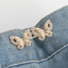 Gold-toned floral butterfly brooch pinned onto a blue denim fabric.
