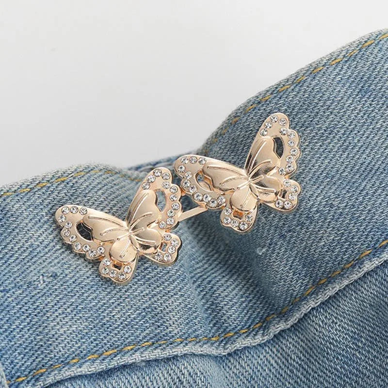 Gold-toned floral butterfly brooch pinned onto a blue denim fabric.