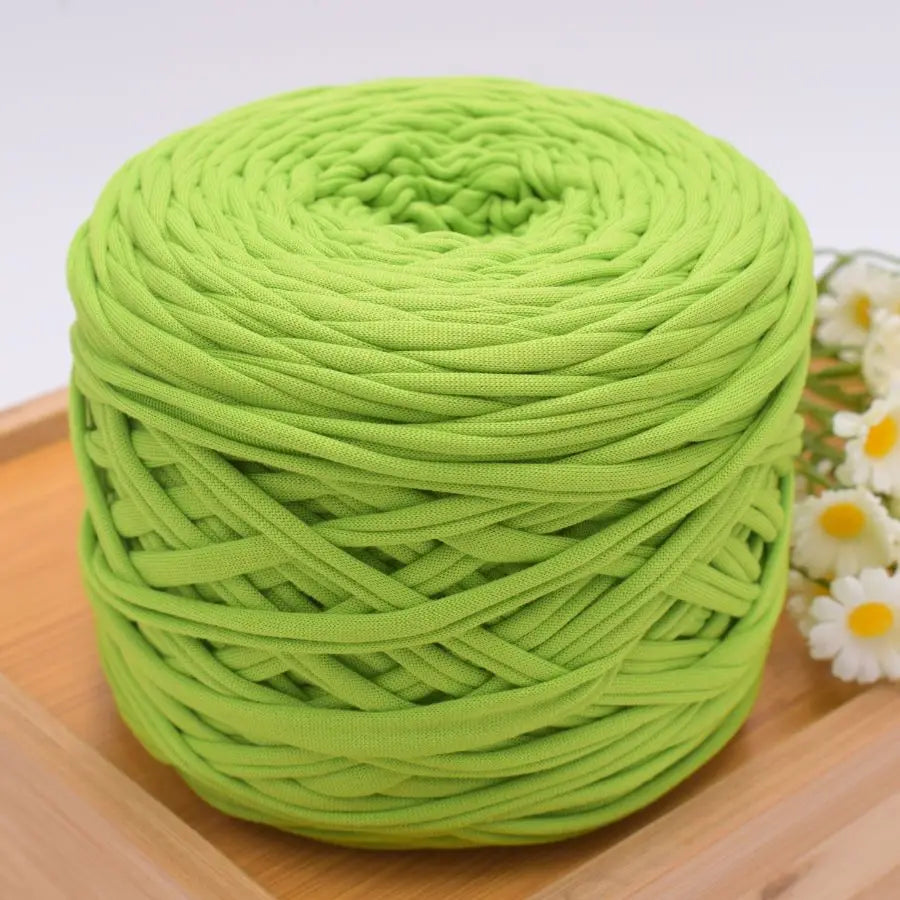 A ball of bright lime green craft yarn for knitting and DIY displayed on a wooden surface.