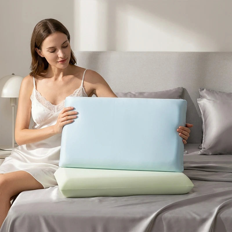 A woman is sitting on a bed with a light blue ice silk cooling pillowcase placed on the sheet.