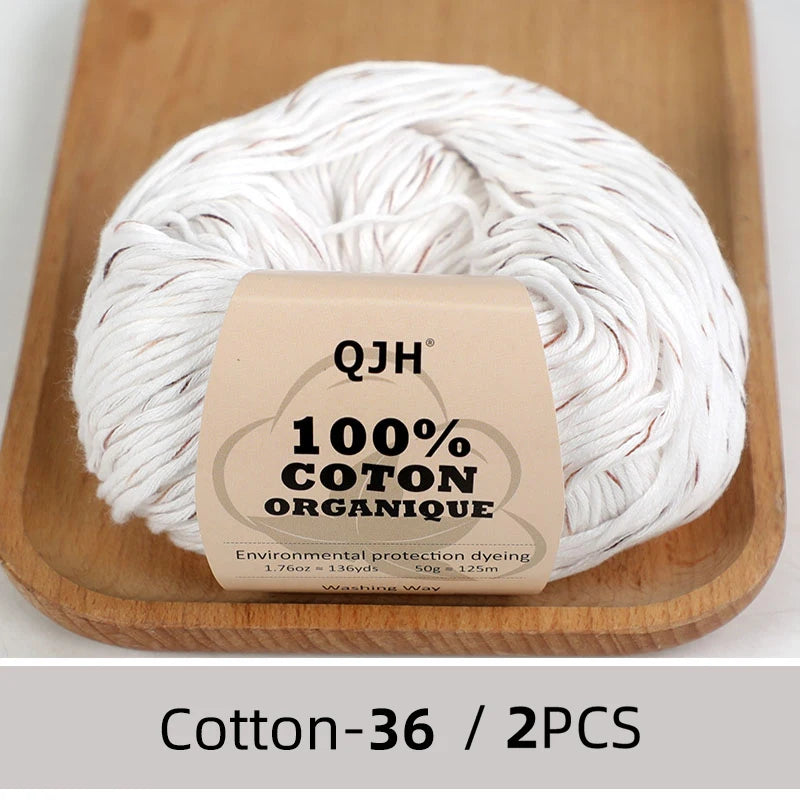 A ball of white organic cotton yarn is displayed on a wooden board.