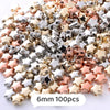A pile of small, colorful geometric acrylic star beads in silver, gold, and rose gold tones.