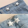 Silver star-shaped adjustable button clips attached to a denim fabric