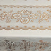 White dining table cloth with delicate brown floral embroidery and lace trim.