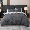 A set of three gray floral print duvet covers and pillowcases displayed on a bed with a dark headboard.