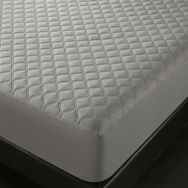 A close-up view of a gray quilted mattress protector placed on a dark surface.