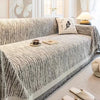 A textured gray jacquard sofa cover blanket draped over a sofa, with a cup and book placed on the fabric.