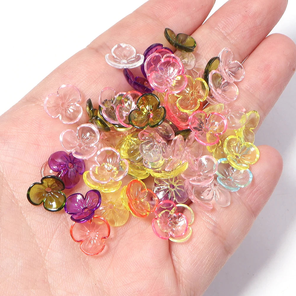 A hand holds a collection of colorful resin flower bead caps for jewelry making.