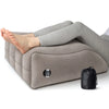A gray inflatable leg elevation wedge pillow is shown supporting a person's legs for pain relief.