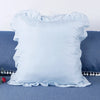 Light blue ruffled pillow covers for bedding displayed on a blue fabric surface.