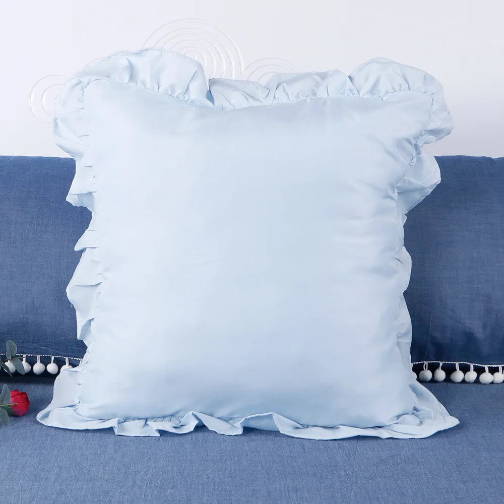 Light blue ruffled pillow covers for bedding displayed on a blue fabric surface.