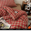 A close-up of a red and green plaid duvet cover set on a bed, with a magazine visible in the foreground.