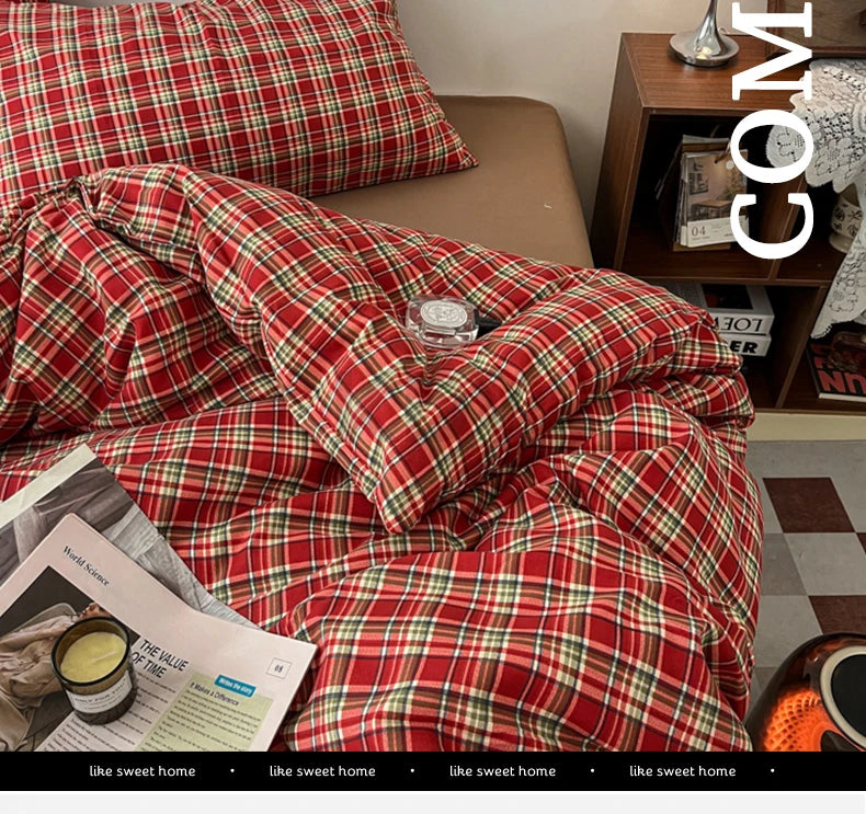 A close-up of a red and green plaid duvet cover set on a bed, with a magazine visible in the foreground.