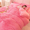 A pink plush mink velvet duvet set with a white teddy bear and a woman relaxing on the bed.