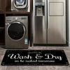 A black laundry mat with white text that reads Wash & Dry or be naked tomorrow placed on a tiled floor.