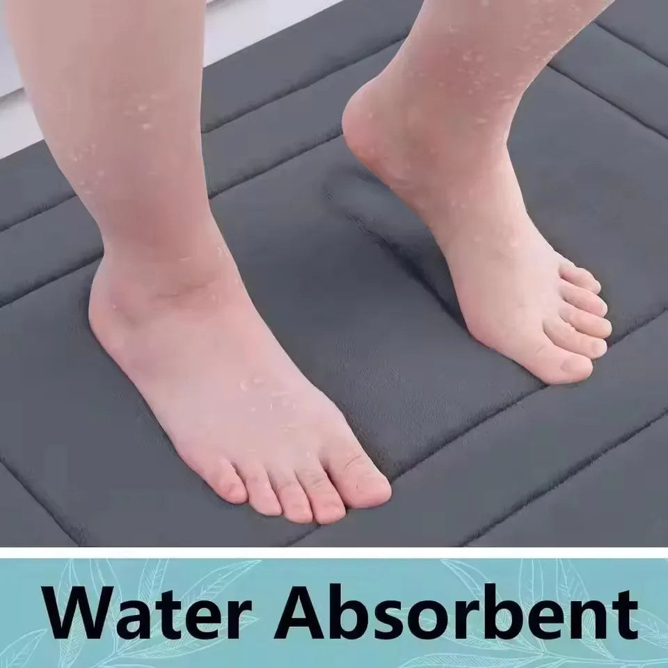 A close-up of a person's foot resting on a dark gray water absorbent memory foam bathroom mat.