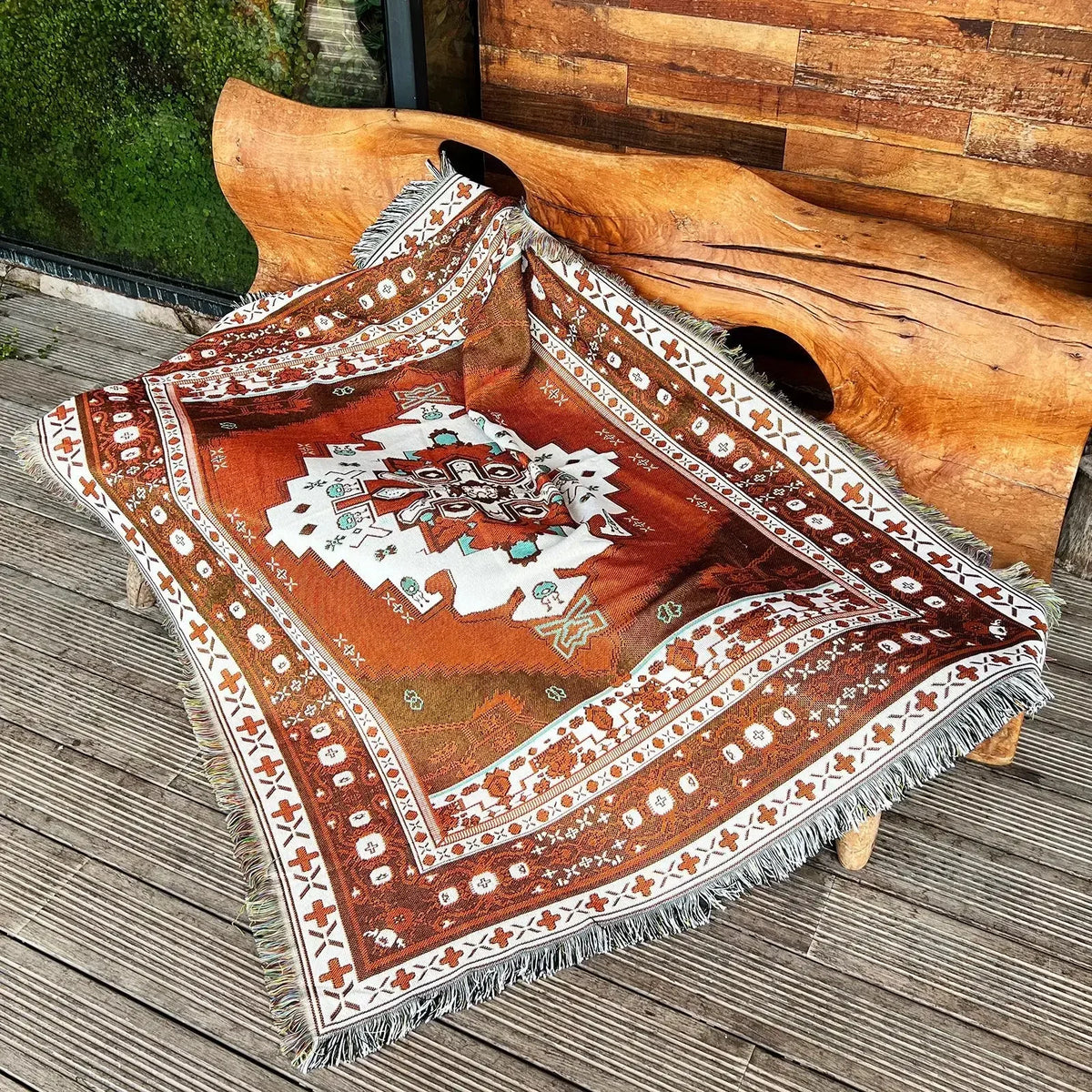 A patterned bohemian geometric throw blanket with earthy tones draped over a large wooden antler.