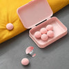 A pink storage box with six round pink clips rests on a yellow fabric surface.