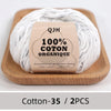 A ball of white organic cotton yarn labeled QJH 100% COTON ORGANIQUE resting on a wooden board.