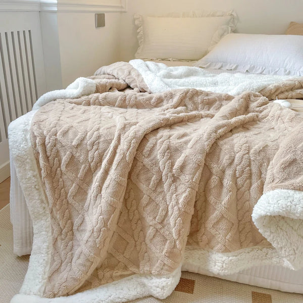 A thick, beige fleece blanket draped over a bed with white bedding and a white radiator visible in the background.