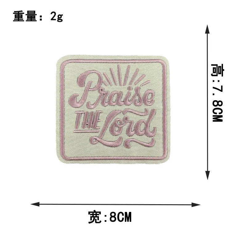 A square embroidered patch with the text Praise the Lord in pink thread on a light beige fabric.
