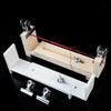 A wooden braiding frame with metal tools and a red string is shown on a black background.