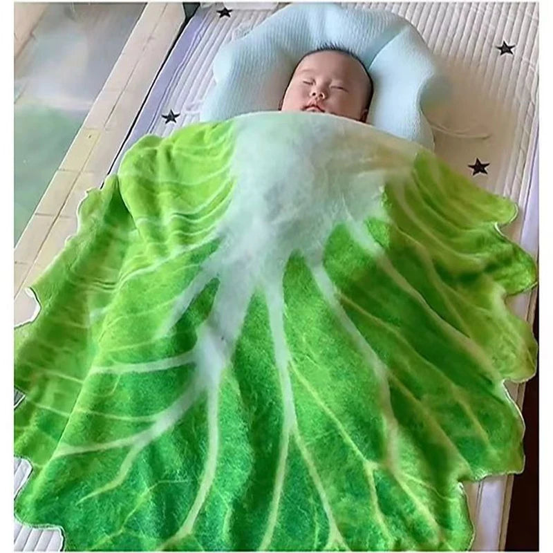 A baby is resting on a green and white leafy patterned plush throw blanket.