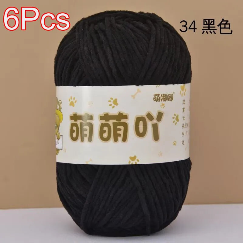 A skein of black soft bulky chenille yarn with gold Chinese characters labeled on the white tag.