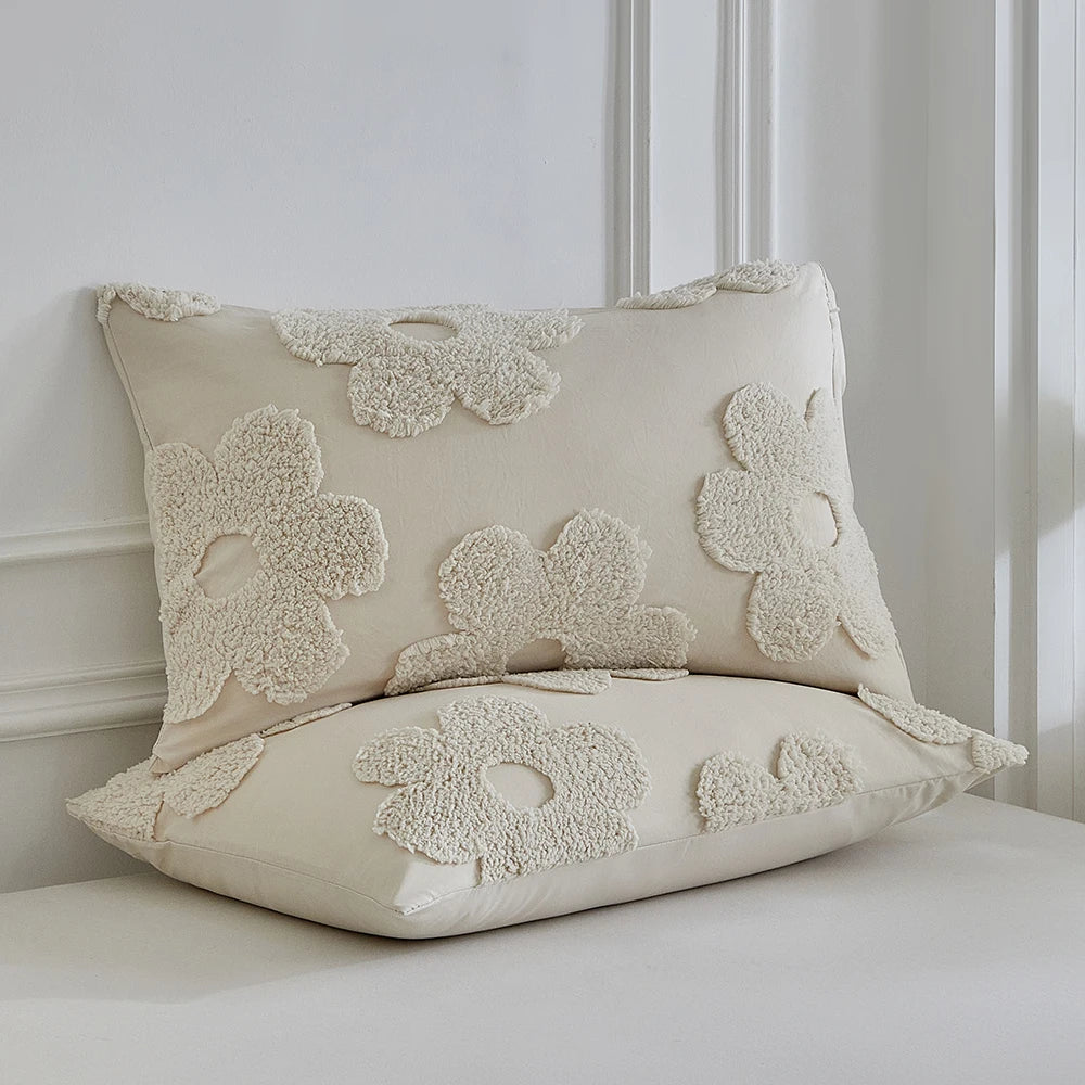 A cream-colored duvet cover set featuring a white tufted floral pattern on the pillowcases.