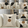 A collection of minimalist geometric line cushion covers in black, beige, and white on a sofa.