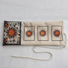 A beige fabric pouch with three framed tarot cards featuring sunburst designs and dark floral elements.