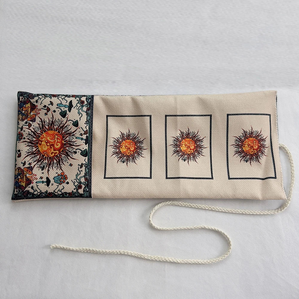 A beige fabric pouch with three framed tarot cards featuring sunburst designs and dark floral elements.