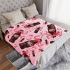 A pink Dr. Pepper print cozy blanket is displayed on a bed with white linens and a gray throw.