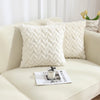 A white jacquard plush throw pillow cover with a geometric chevron pattern resting on a light-colored sofa.